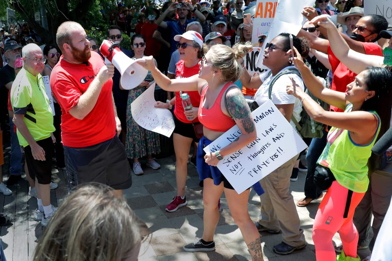 A counter-protester, left in red, is shouted down and has his megaphone taken away by rally attendees for pro-gun control efforts in Houston.