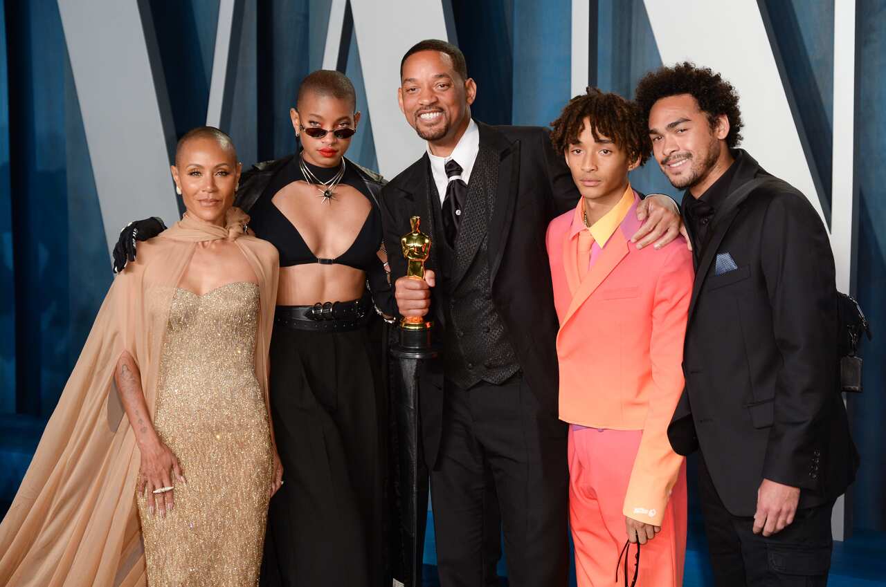 Will Smith is seen holding his Oscar Award while posing for a photo with his family.
