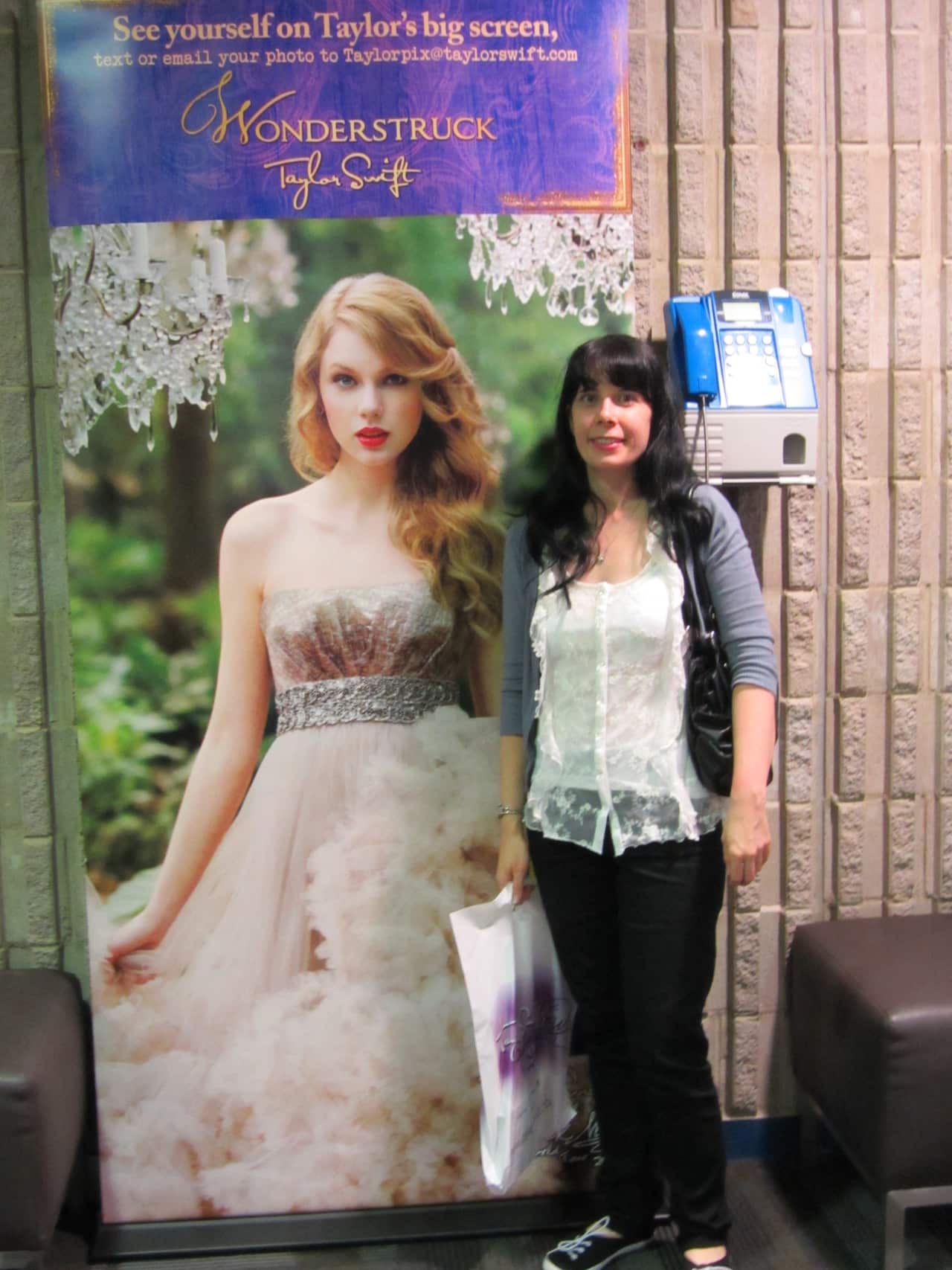 A woman stands next to a poster of Taylor Swift. 