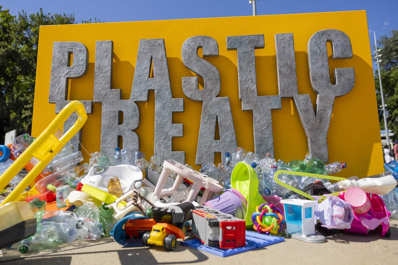 An artwork with plastic items underneath a large plaque that reads "PLASTIC TREATY".