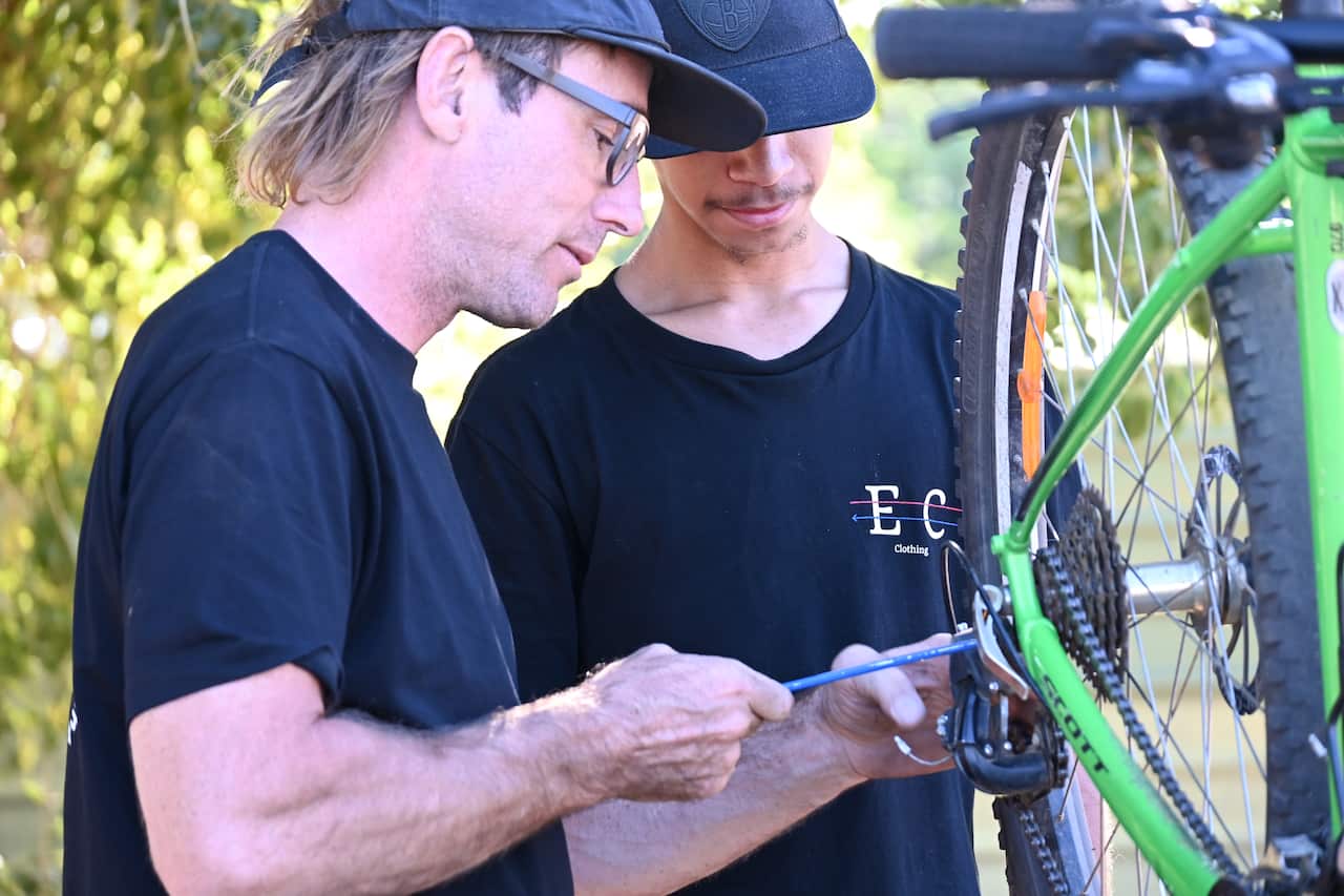 Nathan Walker works on the bike of one of his youth leaders at the Bikes Mwerre program at Lyndavale Park.