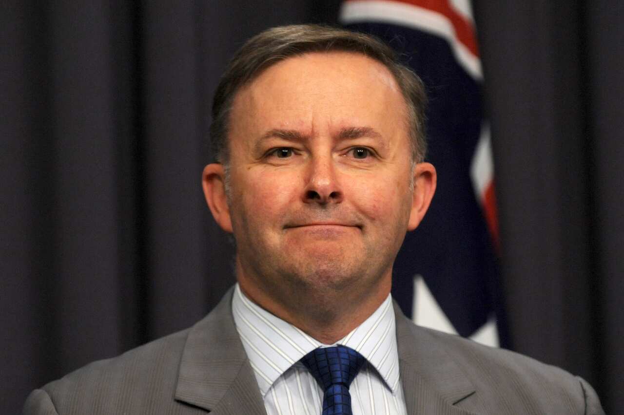 A man wearing a suit and tie standing at a lectern.