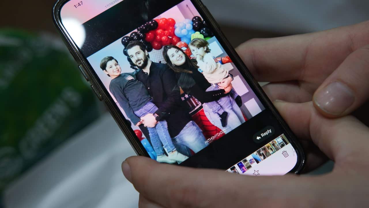 A family photo on a mobile screen shows a couple holding two young boys up in their arms