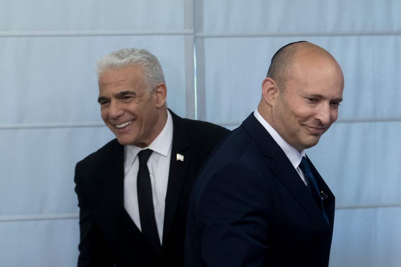 Two men in suits smiling.