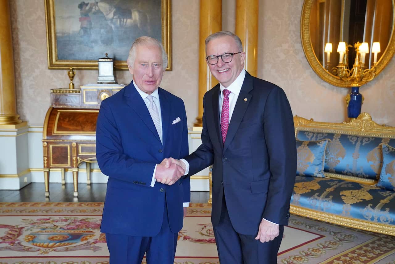 Two men wearing suits and ties are shaking hands.