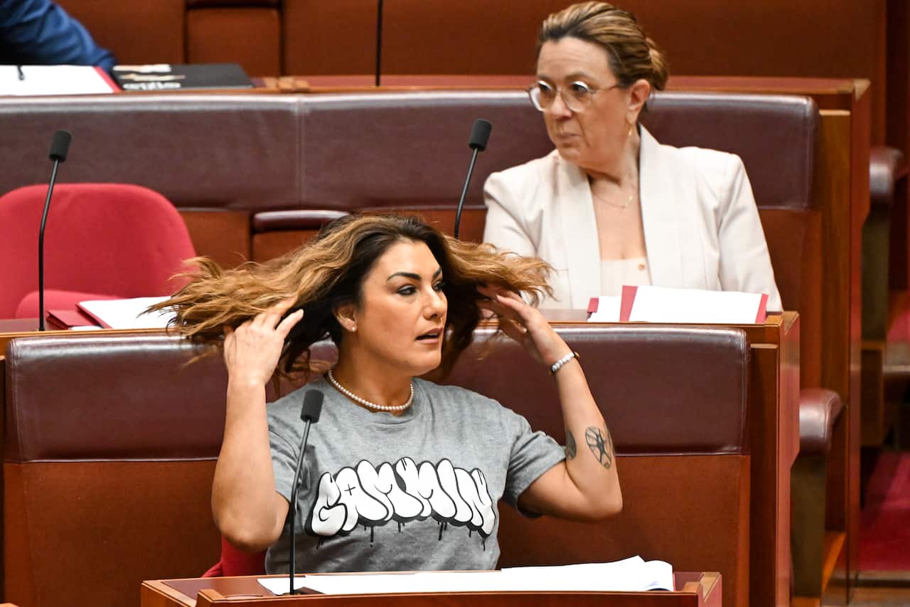 Lidia Thorpe sitting in the Senate. She is wearing a grey t-shirt with the word 'Gammin' written in white