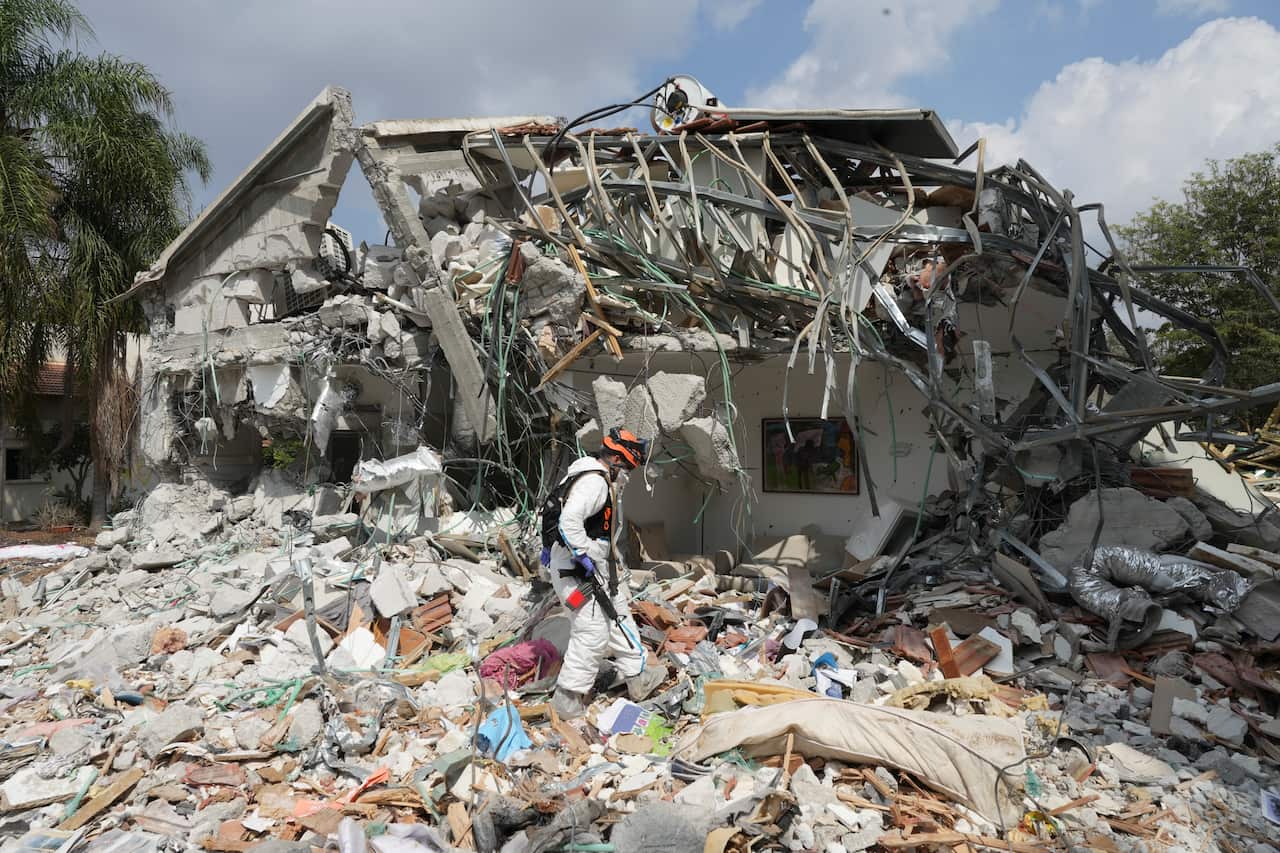 An Israeli soldier walks past a destroyed house.