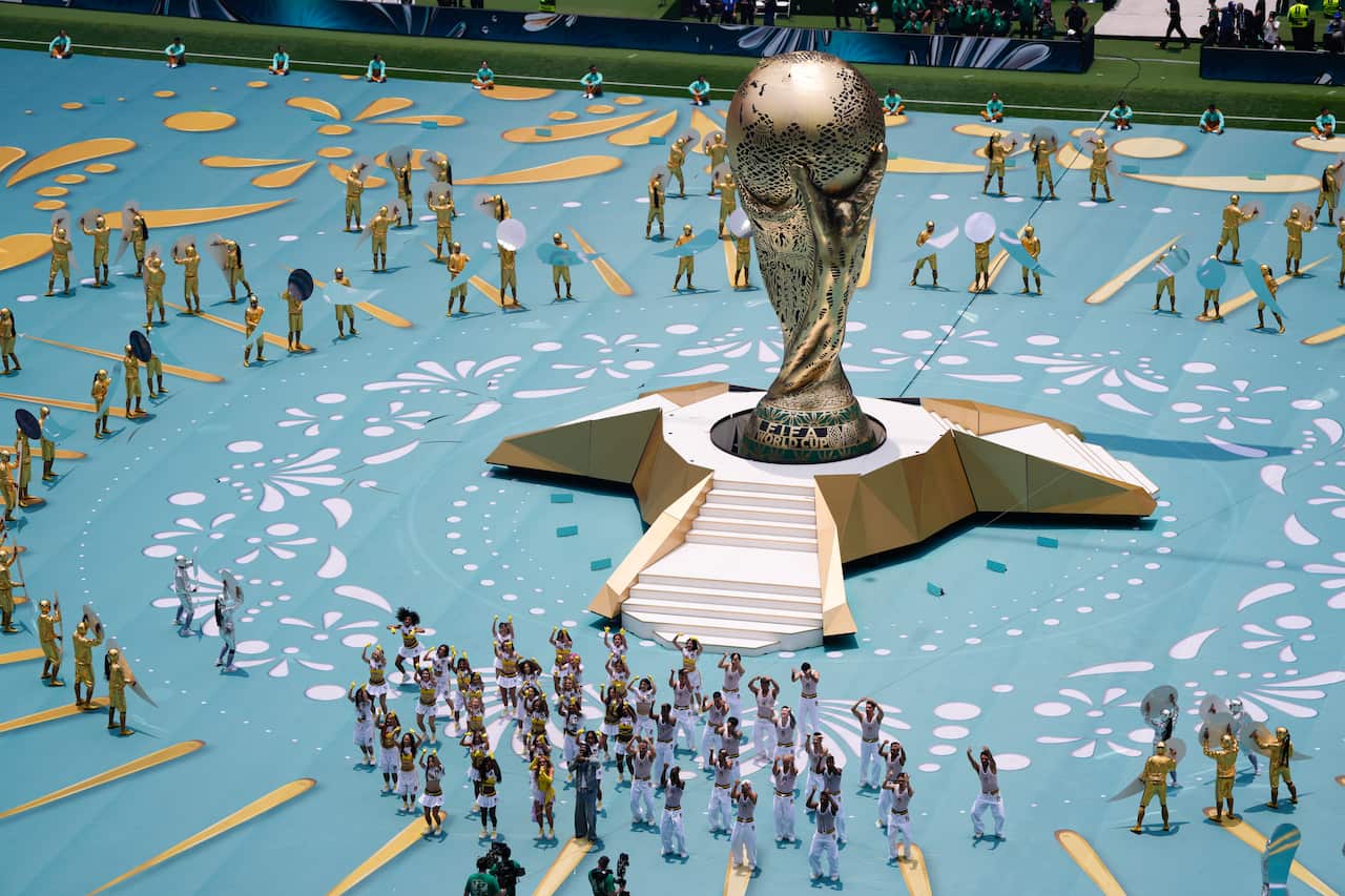 A large golden trophy on a stage with dancers performing around it