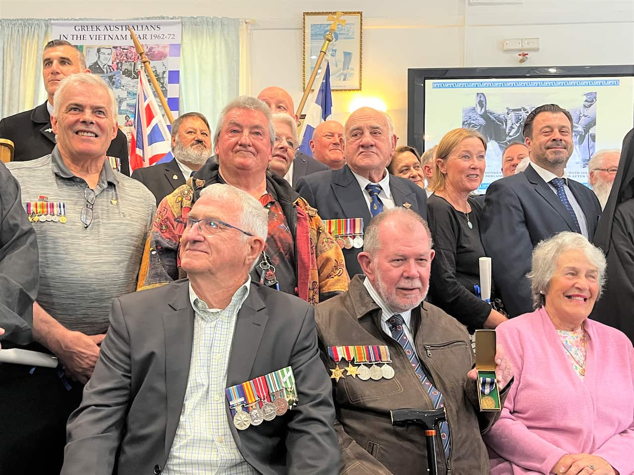 Left, sitting: Michael Byrne, son of Australian veteran Kevin Byrne, photographed with other Australian veterans' families, Hellenic RSL, November 2023, Melbourne 