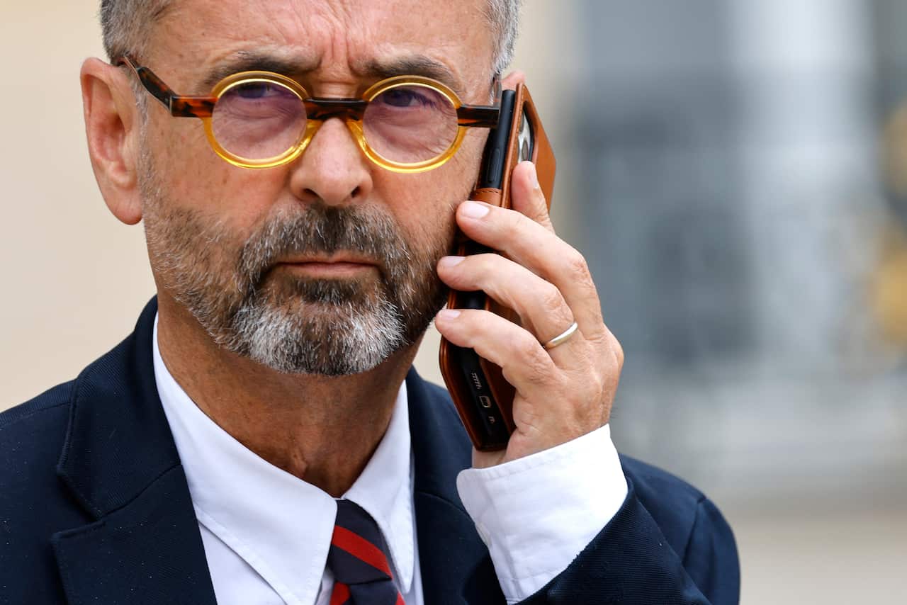 A man wearing a suit, tie, and glasses who is holding his mobile phone to his ear.