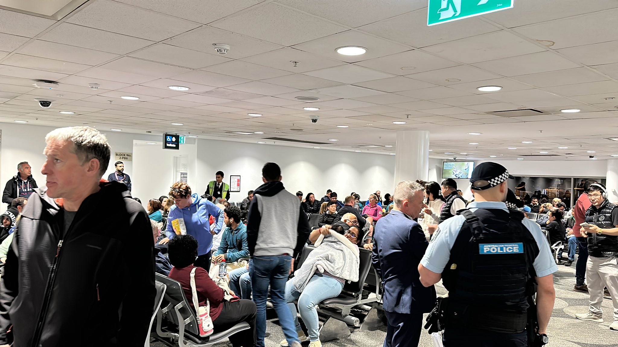 Passengers of a plane sit in the waiting area.