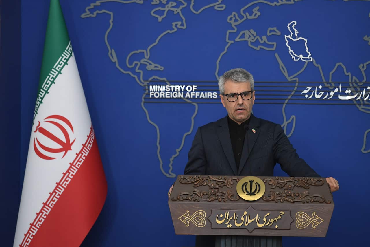 A man speaking at a podium. Behind him is an Iranian flag, and the words "Ministry of Foreign Affairs" are written on a blue wall.