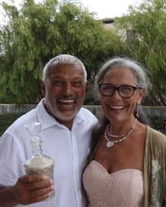 A man and woman embrace as they smile at the camera.