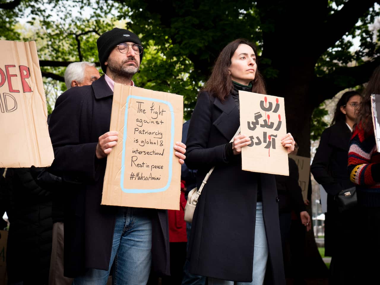 People are seen holding signs at a rally in Hobart following Mahsa Amini's death. 