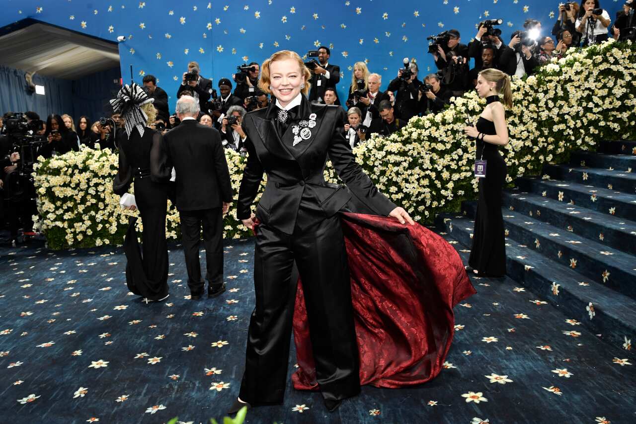 Sarah Snook wearing a black pants suit with a red cape