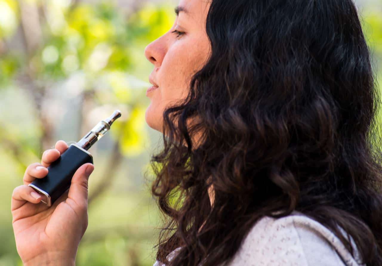 Mature woman outdoors, smoking electronic cigarette
