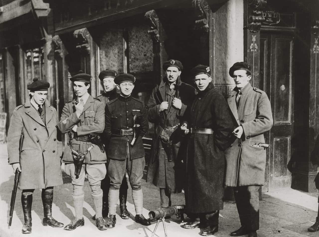 A balck and white photo of a group of soldiers standing in front of a shop