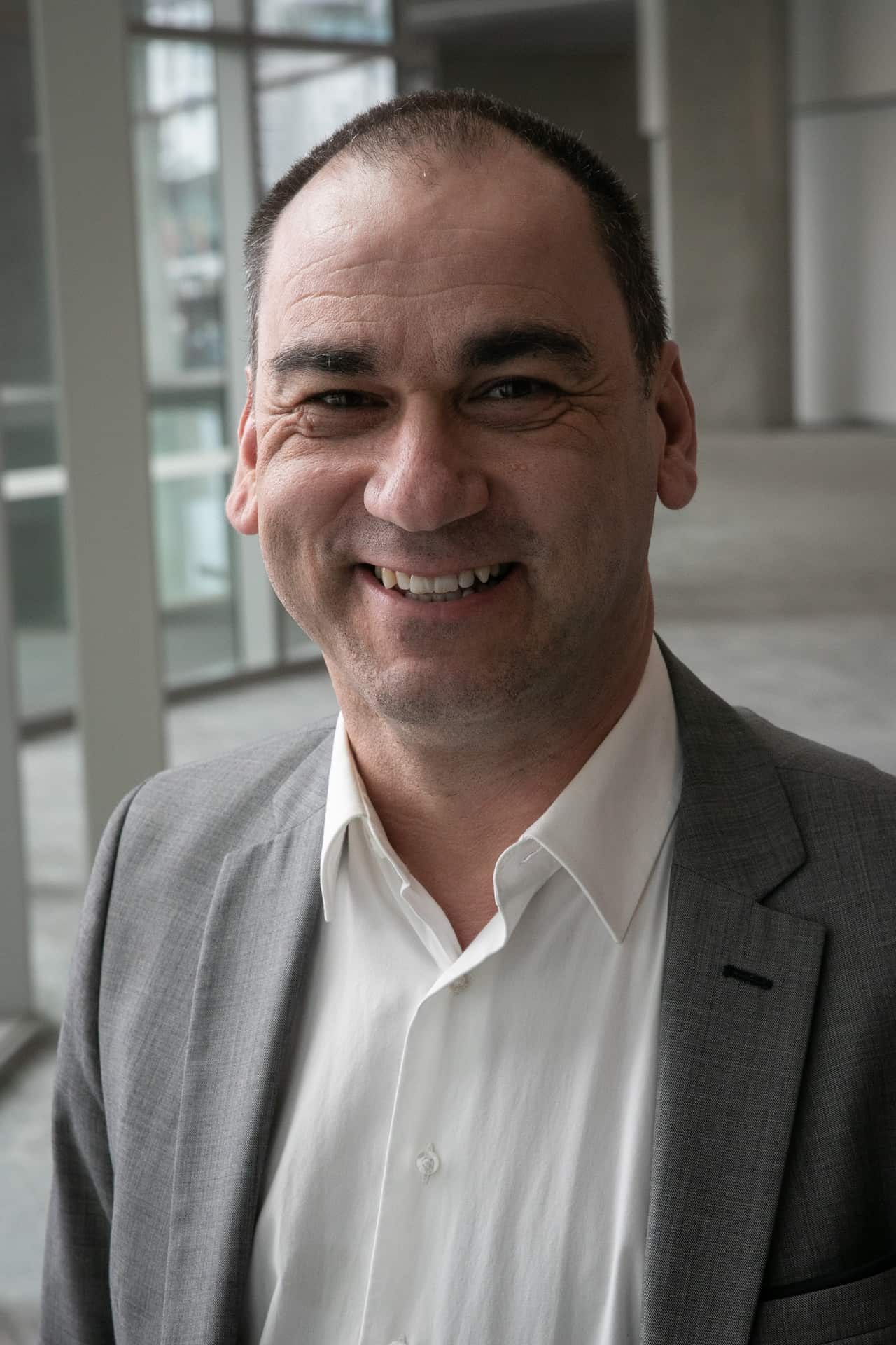 A man in a grey suit jacket and white shirt