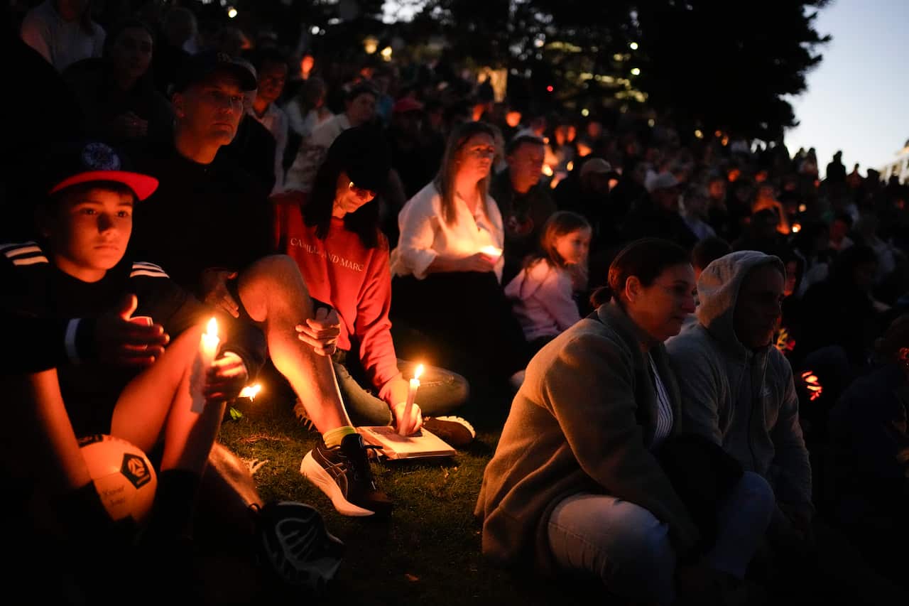 A group of people hold candles during a vigil.