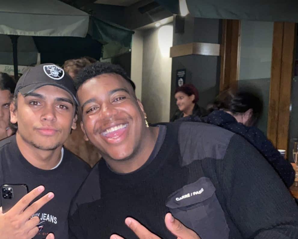 Two young standing next to each other at a party and posing for a photo