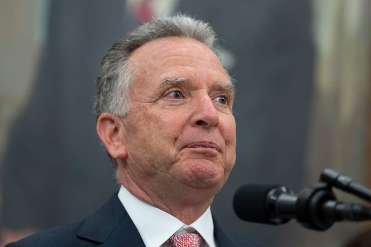 A man with greying hair speaks into a microphone.