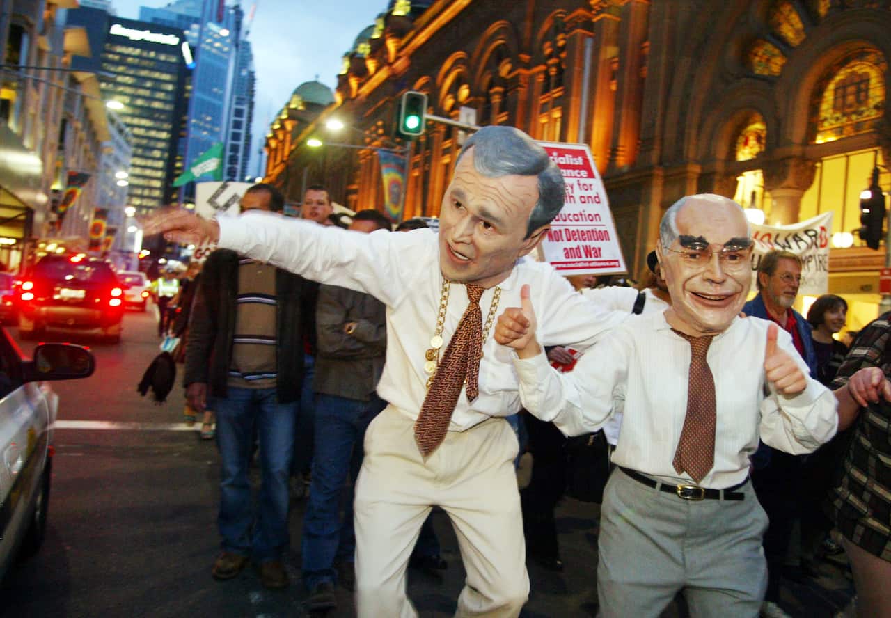 Two men wearing costume heads of George W Bush and John Howard outside Sydney's Queen Victoria building.