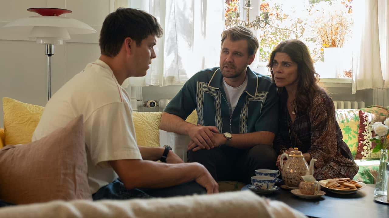 A man sits on a couch opposite and woman and man sitting together