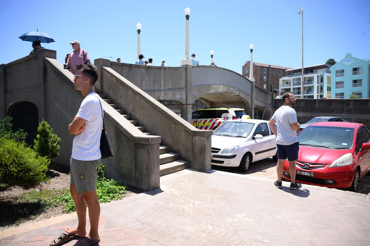 A small staircase leading on to a concrete footbridge with a few people standing on it