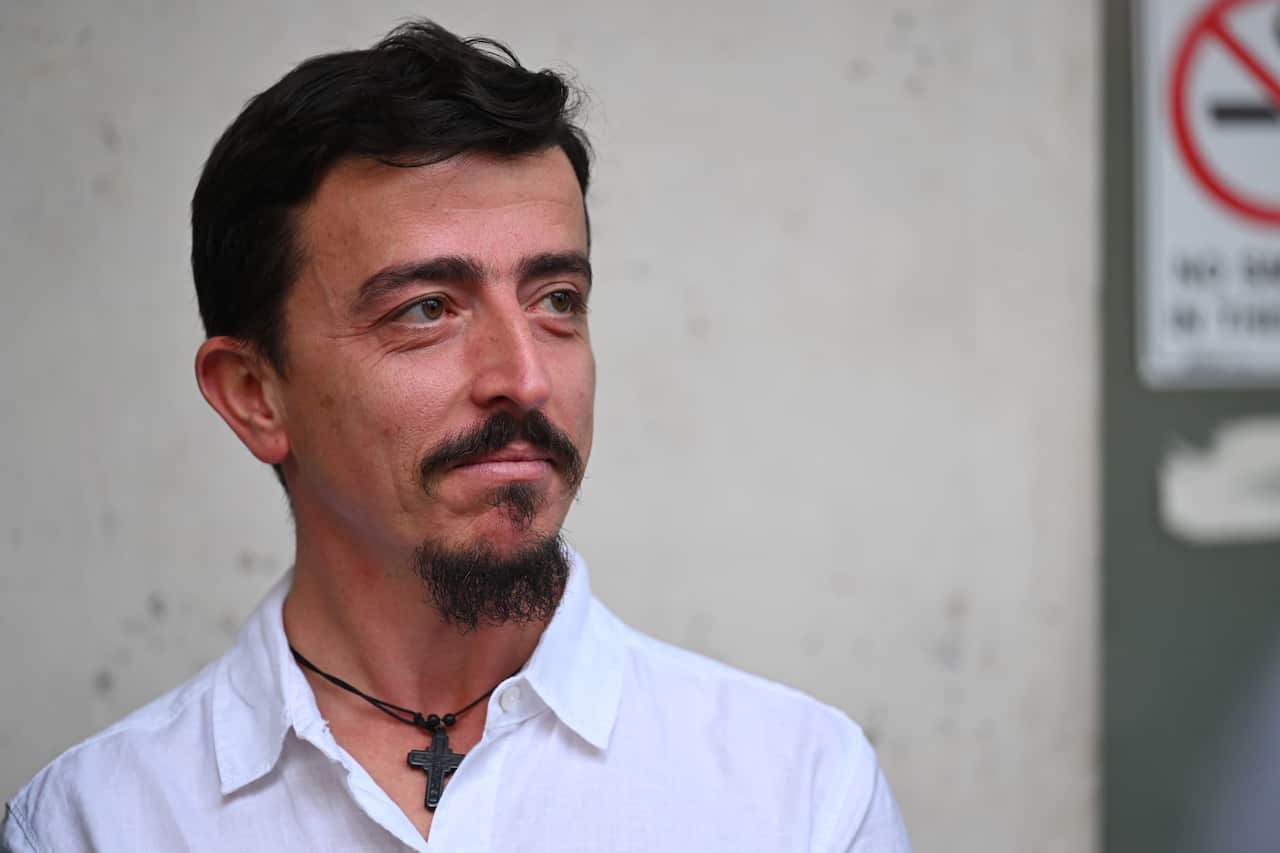 A man wearing a white t-shirt looking to the side.