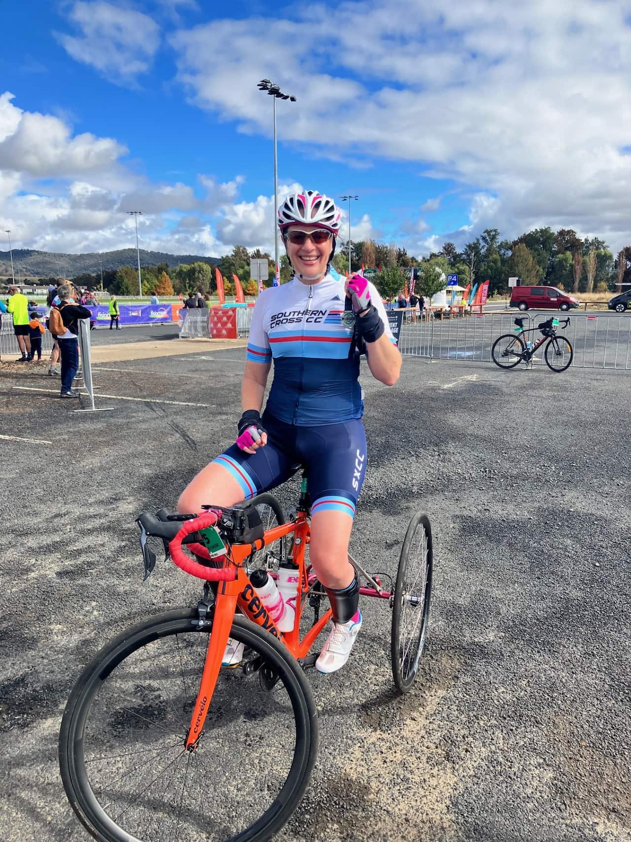 Gabby Vassallo poses with her fist in the air while on her modified bike. She is wearing a helmet and sunglasses.
