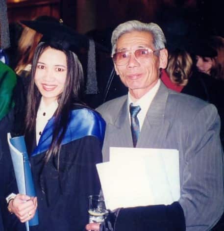 A woman in graduation robes standing with a man.