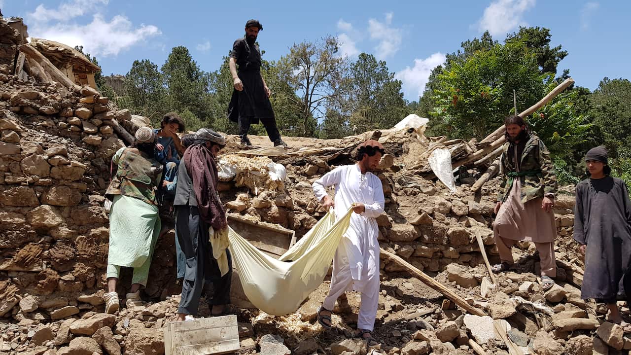 People carry a dead body removed from debris of a building after an earthquake shook Afghanistan