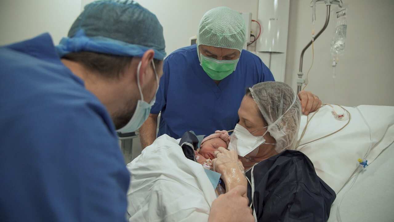 A woman holds her baby in a hospital bed. 