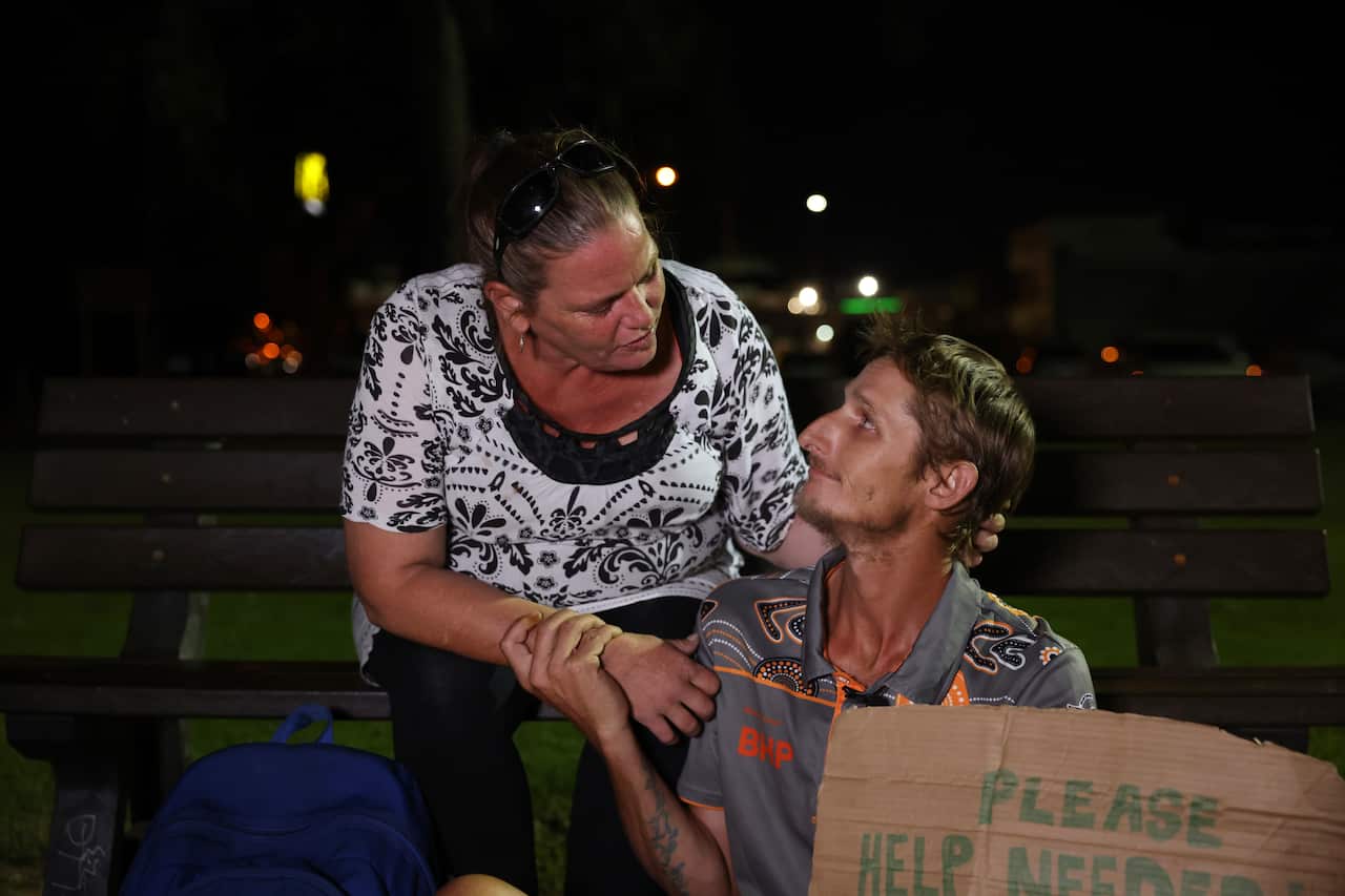 A woman and man hold onto each other closely in a park