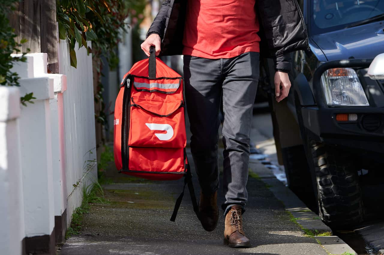 A person walking down a street carrying an insulated bag.