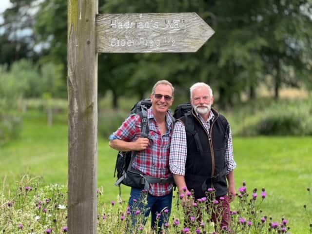 Two grey-haired men stand in a meadow with backpacks on, enjoying a nature walk.jpeg