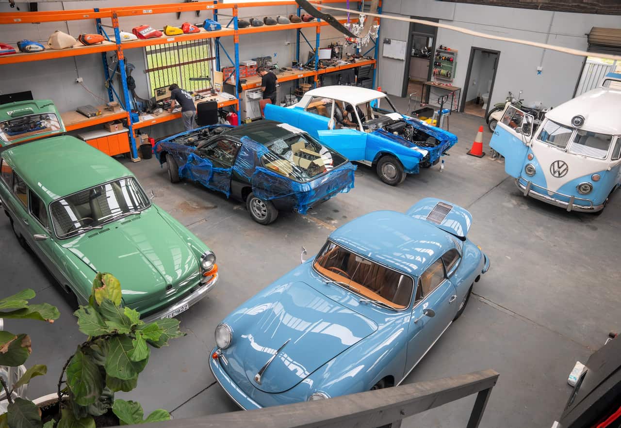 An array of classic cars being work on at a mechanical workshop.