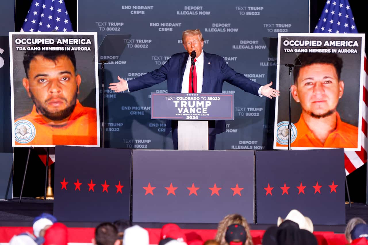 Donald Trump is flanked by photos of alleged gang members at a rally.