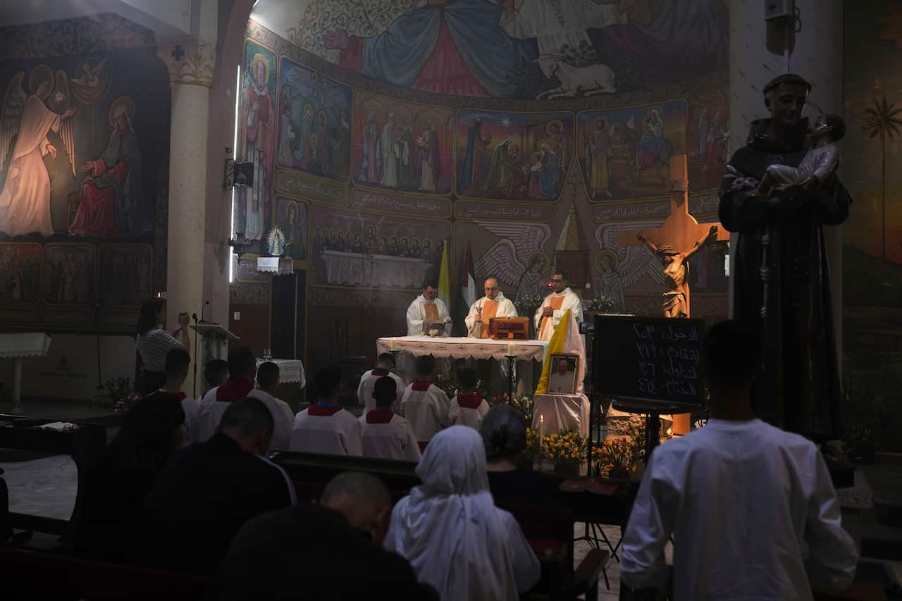 Several clergymen lead a ceremony in a dimly lit church 