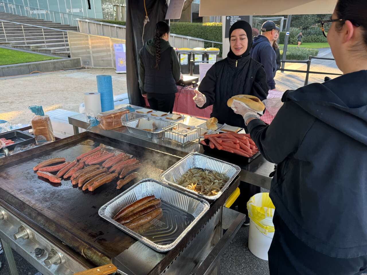 A group of people making hot dogs at a barbecue outside