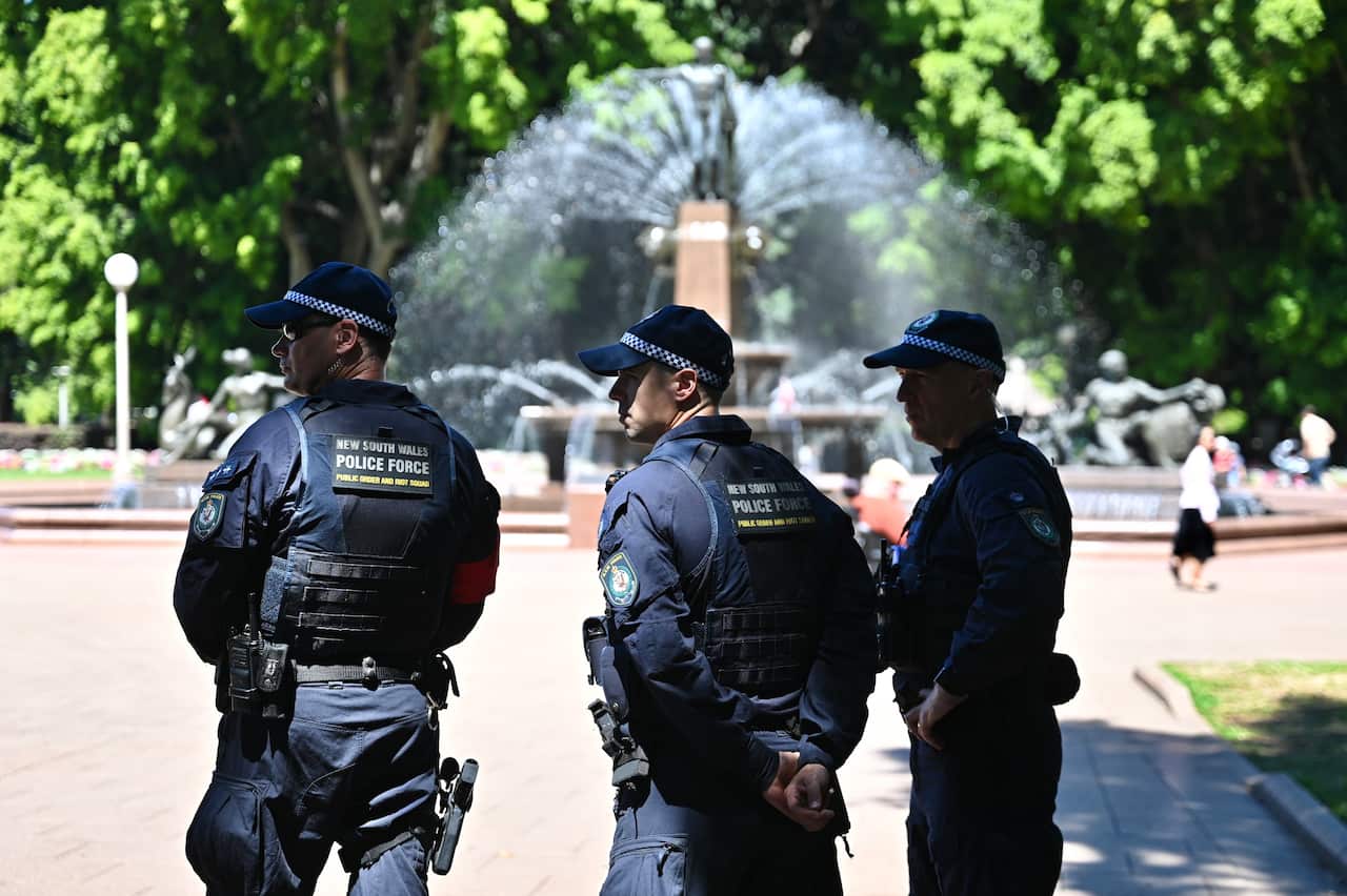 Three police officers observing a rally in a park.