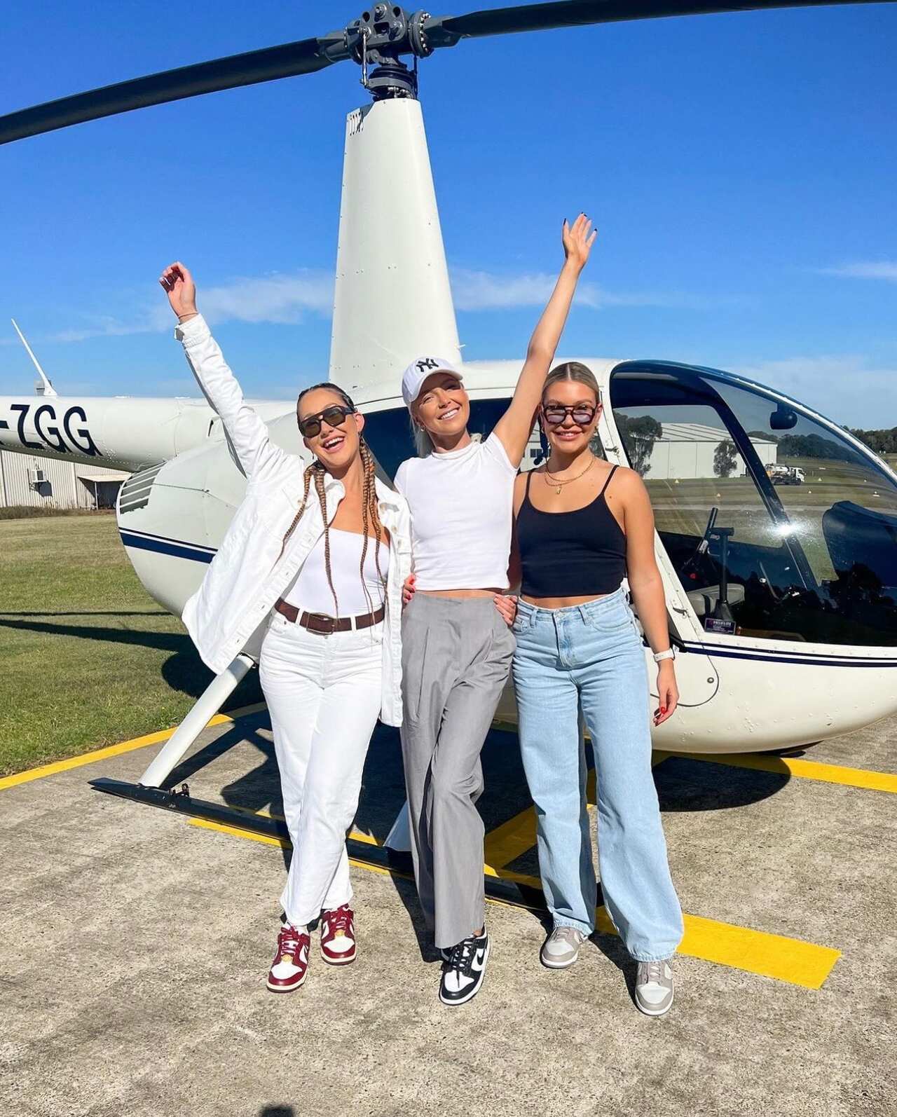 Three girls standing in front of a helicopter