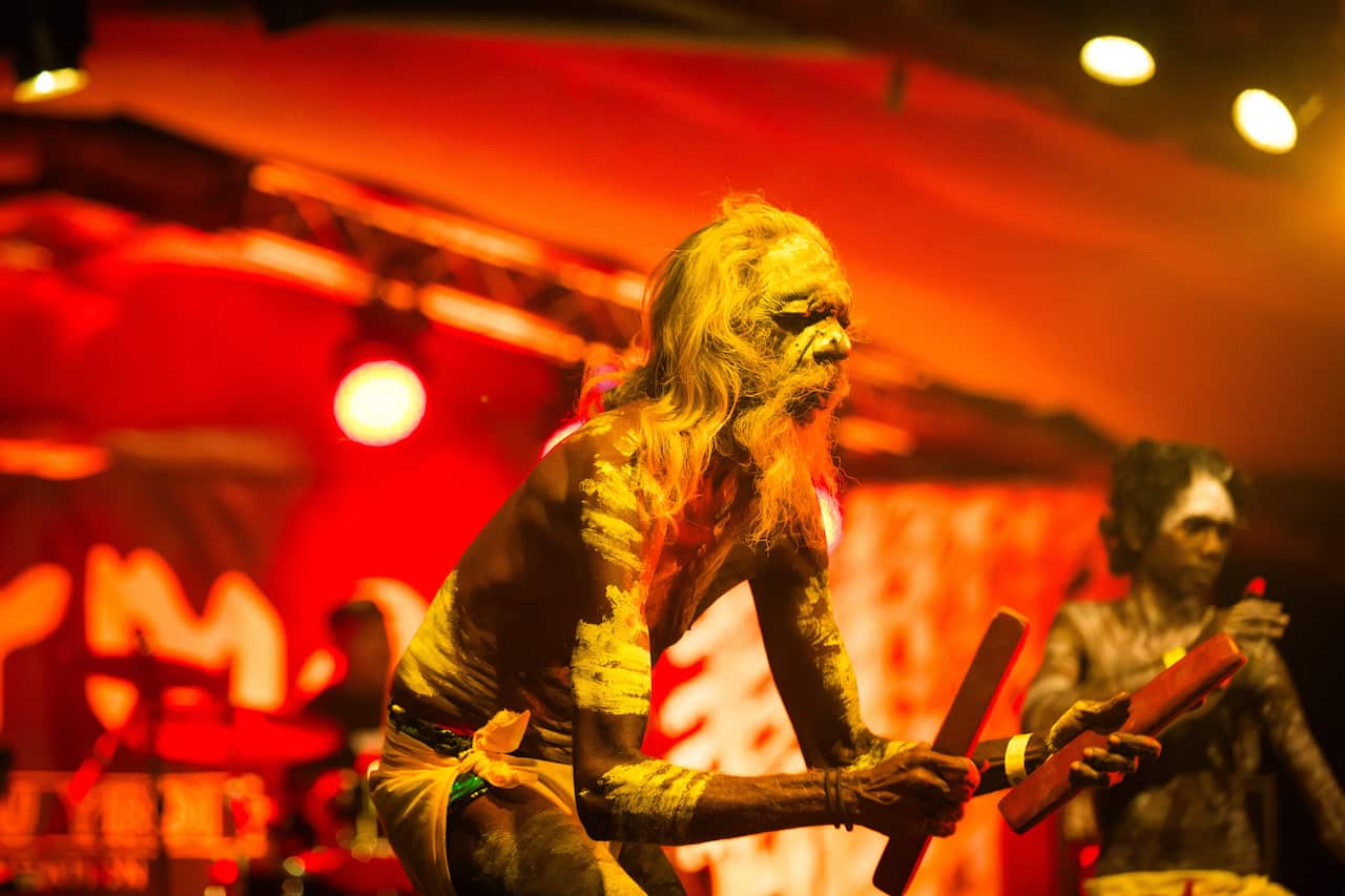 A band of Indigenous performers playing music onstage.