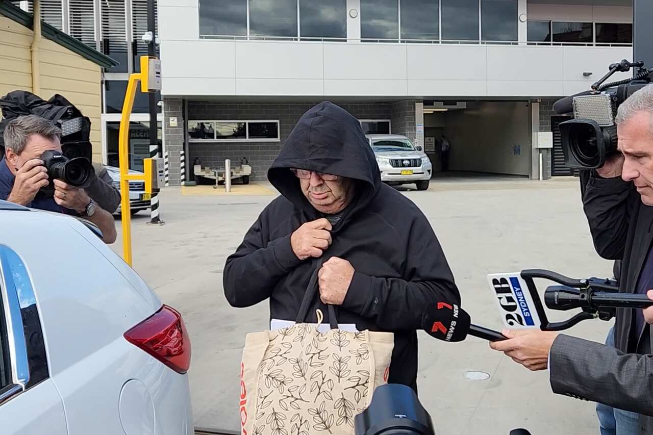 A man in a black hoodie getting into a car
