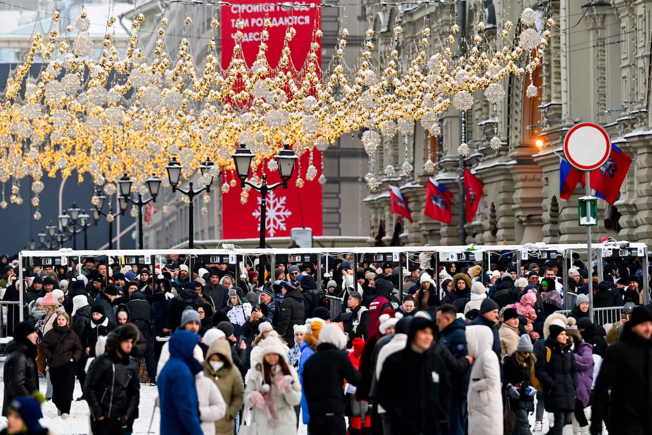 Crowds of people outside a grand historic building in cold weather, with lots of festive lots and banners hanging above,