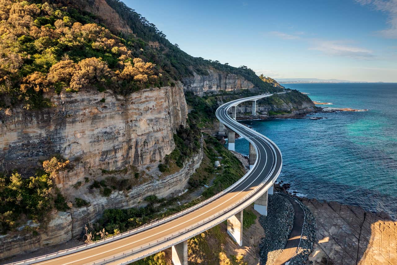 Sea Cliff Bridge, rocky coast road, highway and mountain, aerial view