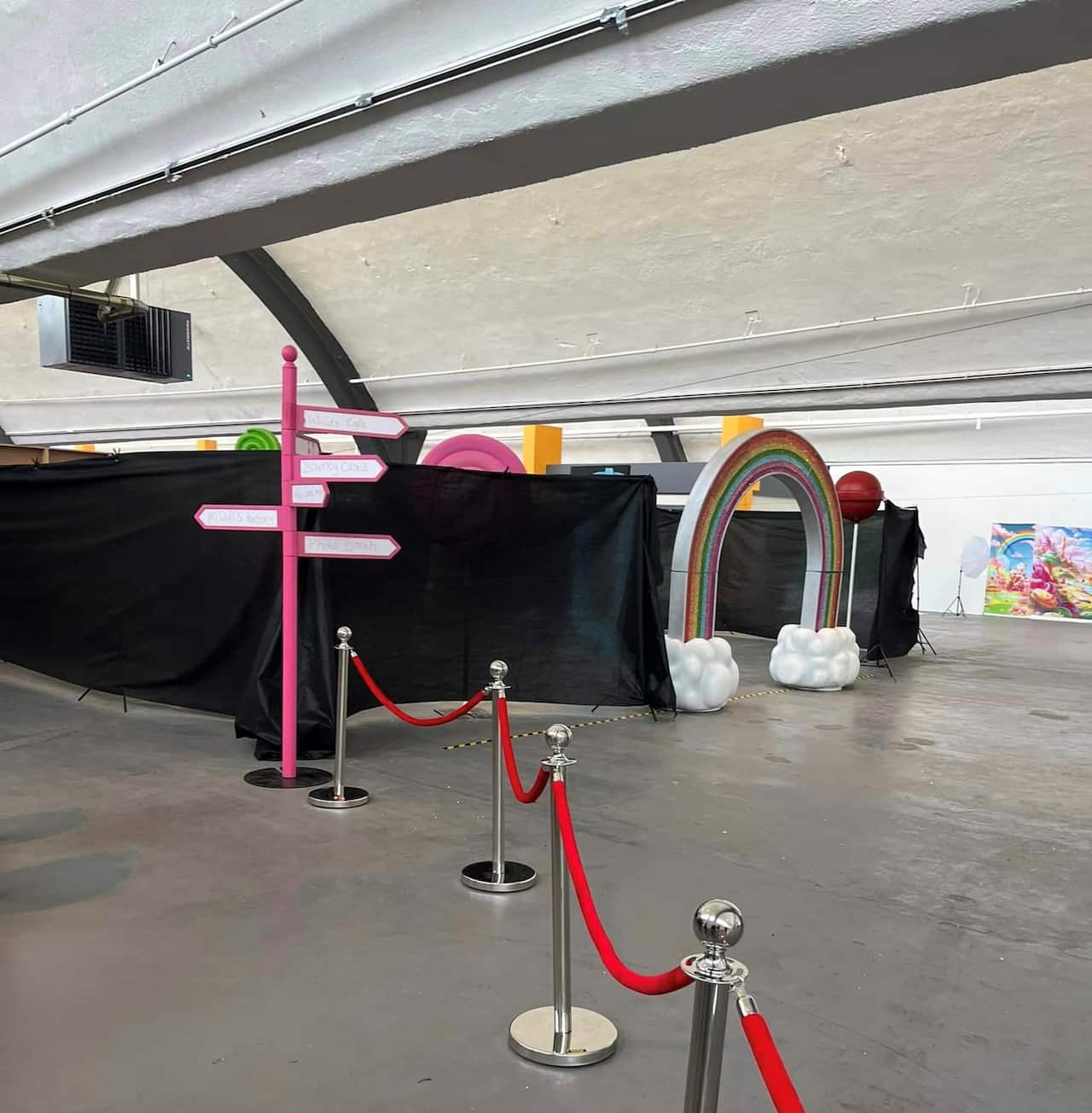 A prop sign post and rainbow arch inside a warehouse.