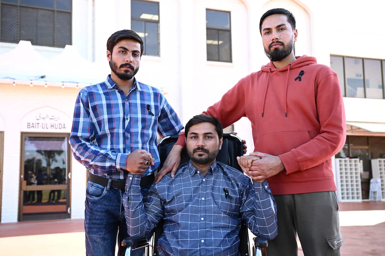 Two men standing and one man seated