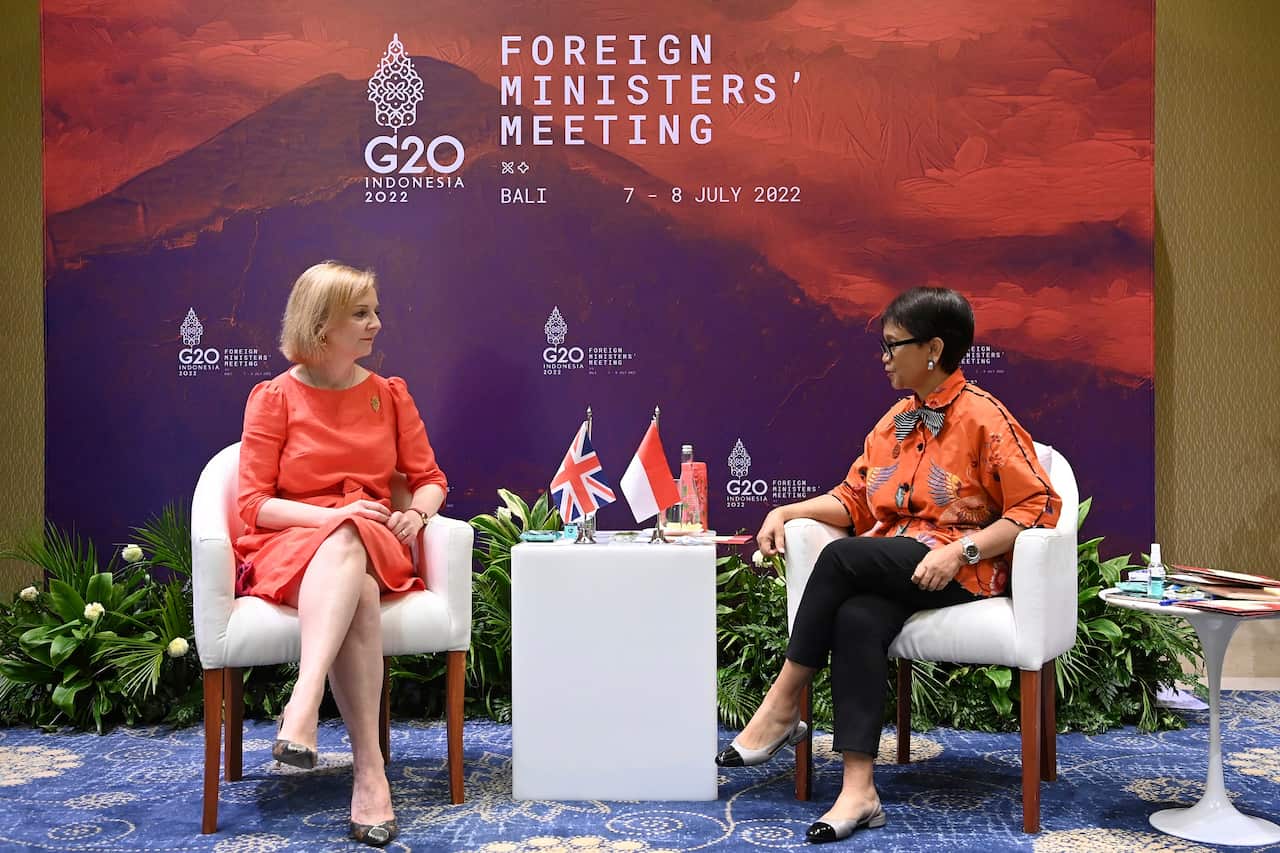 Britain's Foreign Secretary Liz Truss (left) is seated across from Indonesian Foreign Minister Retno Marsudi. Both are seated in chairs in front a sign on the G20 Foreign Ministers' Meeting. 