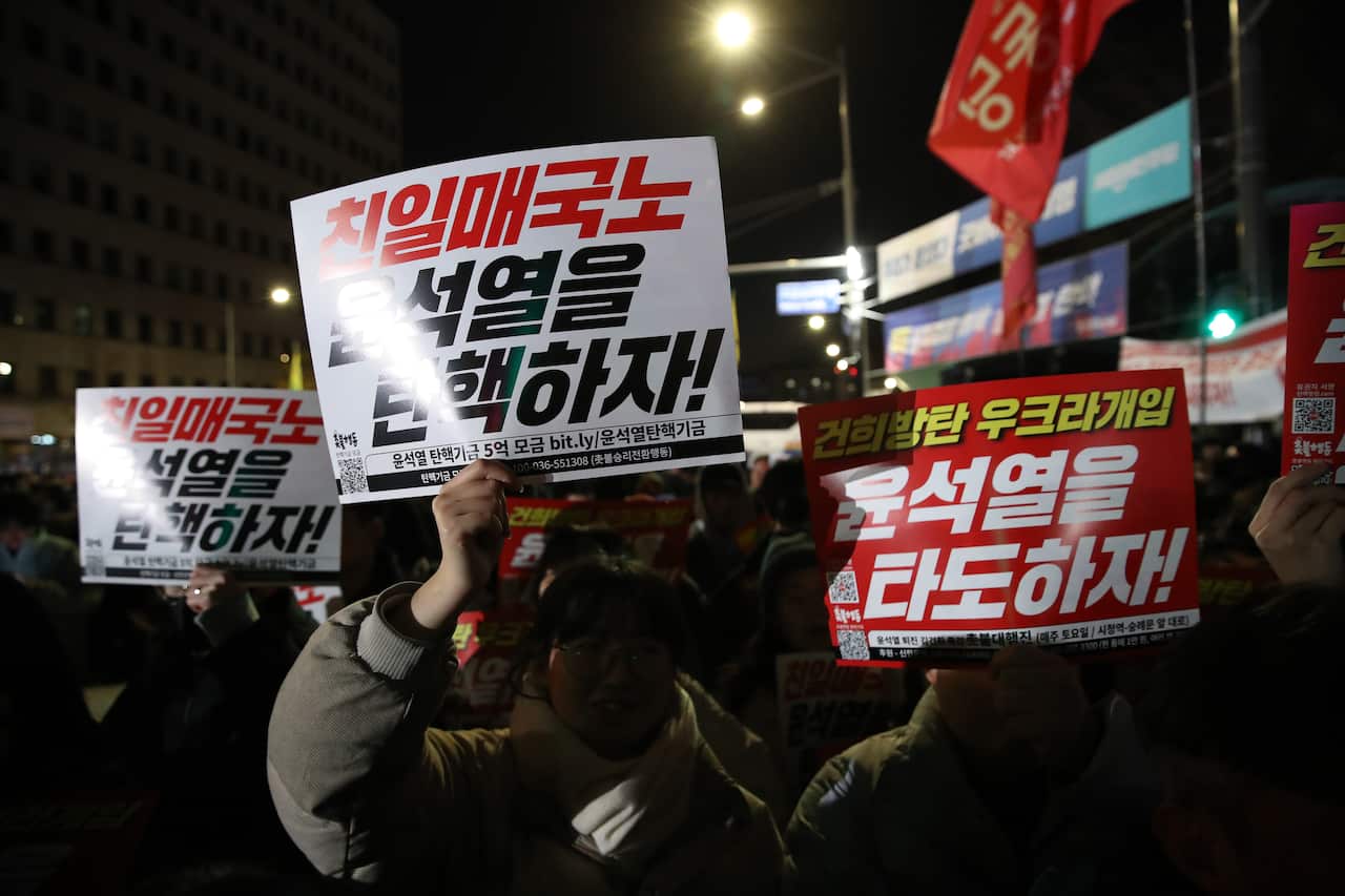 Protesters holding signs calling for South Korean President Yoon Suk Yeol to be overthrown.